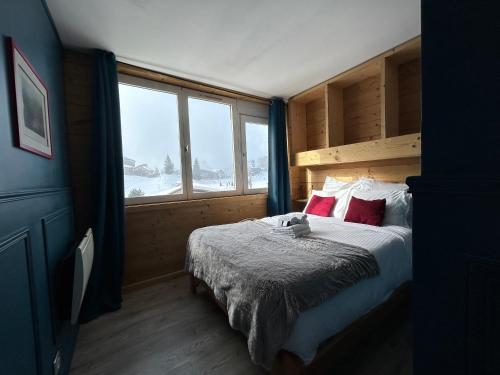 sypialnia z łóżkiem z czerwonymi poduszkami i oknem w obiekcie Résidence Les Portes du Soleil - Propriétés Mont Amour w mieście Avoriaz