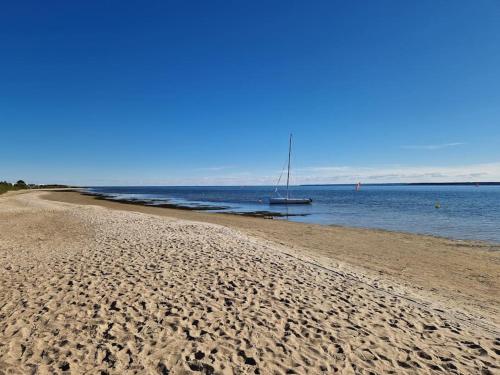 a sandy beach with a sail boat in the water at Kite House Chałupy in Władysławowo