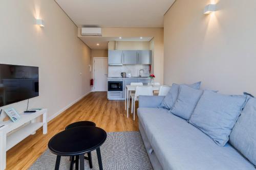 a living room with a blue couch and a kitchen at Setubal Prime in Setúbal