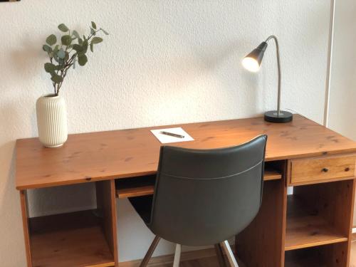 un bureau en bois avec une lampe et une chaise dans l'établissement LIME HOMES: Balkon, Küche, Netflix, à Barsinghausen