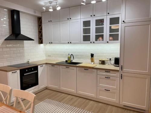 cocina con armarios blancos, fregadero y fogones en APARTAMENTY GUZIK 22, en Krosno