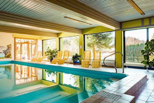 - une piscine dans une maison aux murs jaunes dans l'établissement Landhotel GrünWies -Bonsai-Wellness Garni, à Lohberg