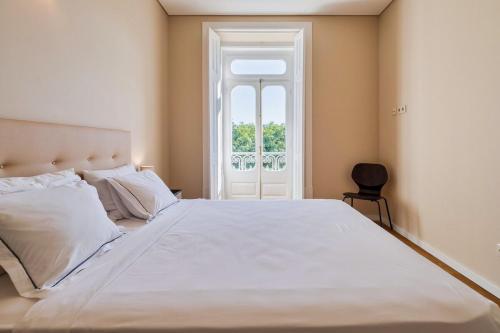 a bedroom with a large white bed and a window at Setubal Prime in Setúbal