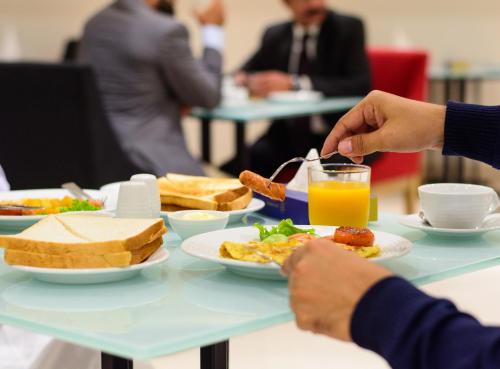 einen Tisch mit Teller mit Lebensmitteln und ein Glas Orangensaft in der Unterkunft Hotel Excelsior Karachi in Karatschi