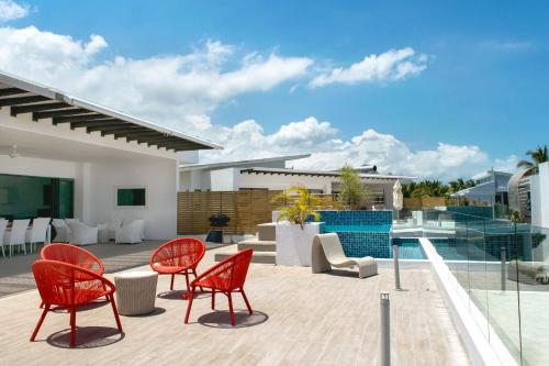 a patio with red chairs and a pool at Cap Ouest by Horizon Holidays in Flic-en-Flac