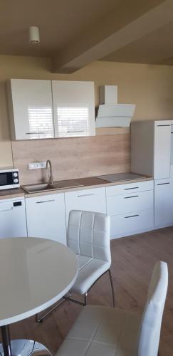 une cuisine avec des placards blancs et une table et des chaises blanches dans l'établissement Apartmán Greenside, à Michalovce