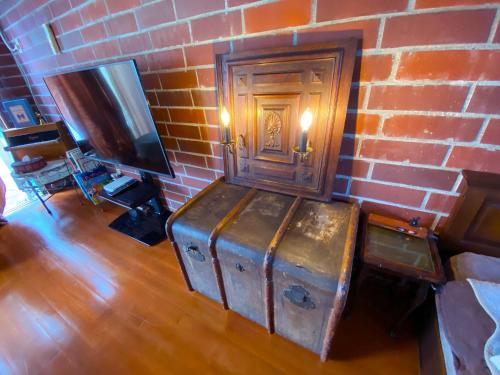 a room with a brick wall with a trunk and a television at 猫とピアノと星空のリゾートブティックコテージ - Starry Forest Cottage Okinawa - in Onna