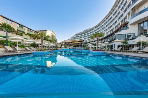 einem Pool mit Stühlen und Sonnenschirmen vor einem Gebäude in der Unterkunft Seaden Quality Resort & Spa Ultra All Inclusive in Side