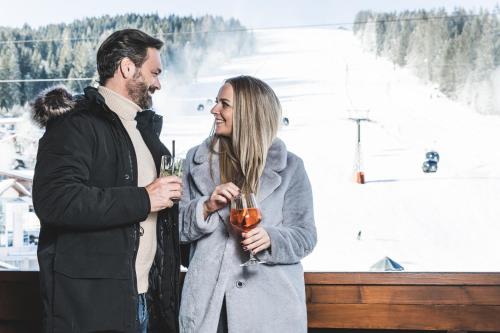 Ein Mann und eine Frau mit Weingläsern. in der Unterkunft Alpines Gourmet Hotel Montanara in Flachau