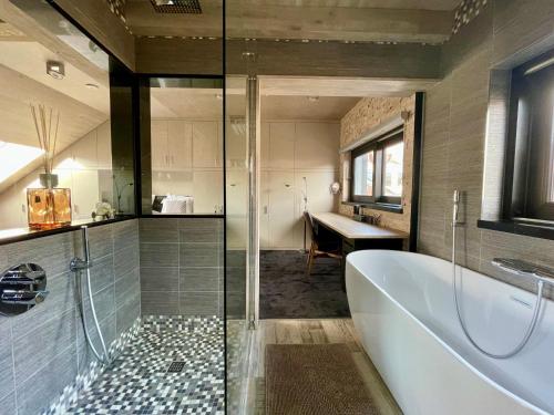 a bathroom with a tub and a sink and a desk at Guesthouse ROOM40 in Malmedy