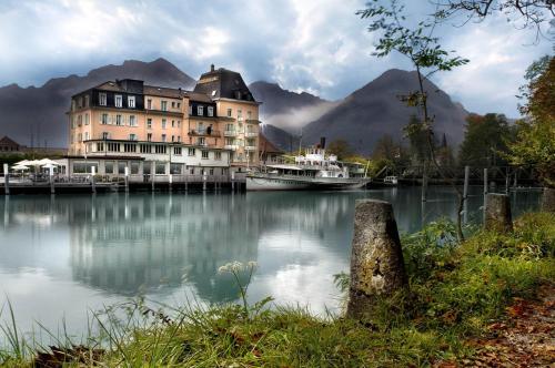 ein großes Gebäude neben einem See mit Booten darin in der Unterkunft Hotel Du Lac in Interlaken