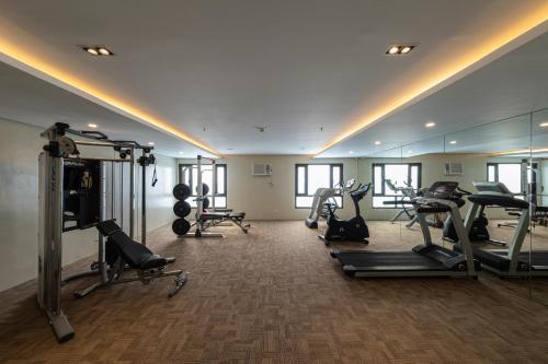 einen Fitnessraum mit mehreren Laufbändern und einem Spiegel in der Unterkunft Cebu Family Suites powered by Cocotel in Cebu City