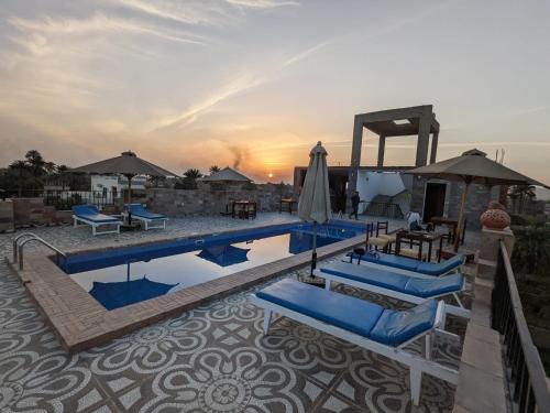 - une piscine avec des chaises et des parasols et le coucher du soleil dans l'établissement Nile Panorama Hotel, à Louxor