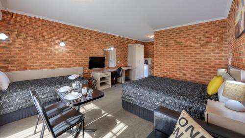 ein Hotelzimmer mit 2 Betten und einem Esszimmer in der Unterkunft Glider City Motel Benalla in Benalla