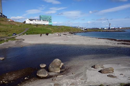 uma praia com pedras na água e um edifício em Autocamper Tórshavn em Tórshavn