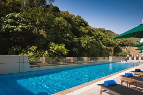 una grande piscina con sedie e ombrellone di Nina Hotel Island South a Hong Kong