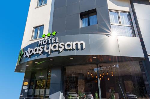 伯萨Görükle Alpaş Yaşam Hotel的酒店大楼前的奥迪赛乌兹别克标志牌