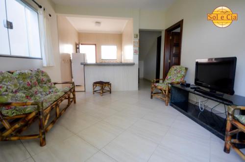 a living room with chairs and a flat screen tv at Pousada Sol e Cia Tur in Caraguatatuba