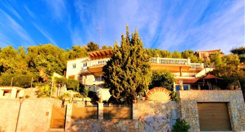 une maison avec un arbre devant une clôture dans l'établissement Ashram Villa Sunshine, à Sitges