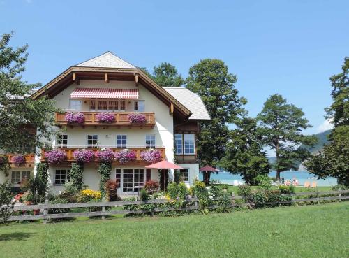 une maison avec des fleurs sur son côté dans l'établissement Landhaus Leitner am Wolfgangsee, à Sankt Gilgen