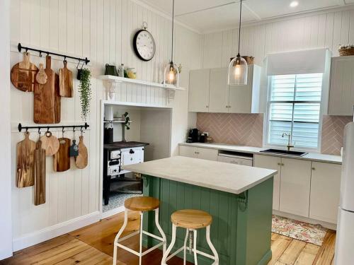 uma cozinha com uma ilha verde e dois bancos em Gorgeous Arthouse Queenslander In Ipswich em Bundamba