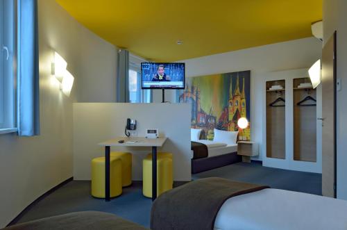 um quarto de hotel com uma cama e uma mesa e uma televisão em B&B HOTEL Erfurt-Hbf em Erfurt