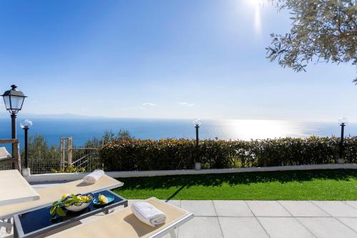 un patio con tavolo e l'oceano sullo sfondo di Holidays Perla d'Amalfi ad Amalfi