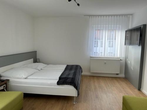 Habitación blanca con cama y TV en Aparthotel Gartenstadt, en Bamberg