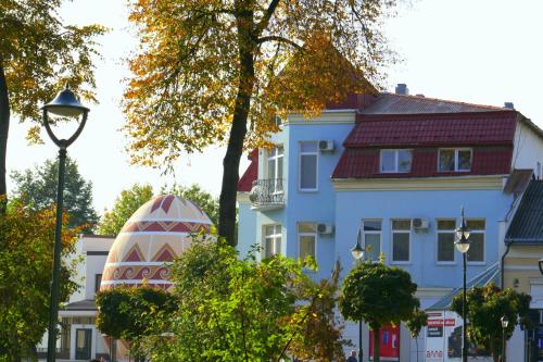 un bâtiment blanc avec un toit rouge et un arbre dans l'établissement Pysanka Hotel, à Kolomya