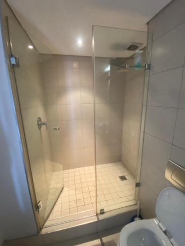 une douche avec une porte en verre à côté des toilettes dans l'établissement 608 Beacon Rock, à Durban