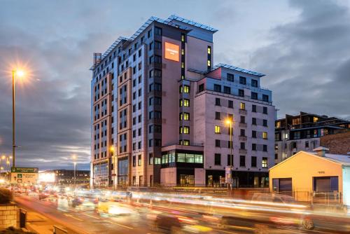 un edificio alto en una concurrida calle de la ciudad con tráfico en Leonardo Hotel Nottingham en Nottingham