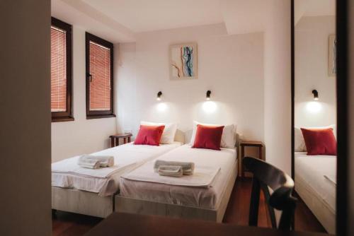 two beds in a small room with red pillows at Hotel Castrum in Skopje