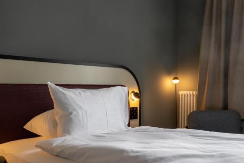 een bed met een wit kussen en een stoel bij Boutique Hotel Waldhaus beider Basel in Bazel