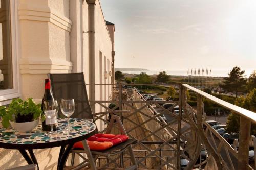 una mesa con una copa de vino en el balcón en Villa Seeblick Warnemünde - Fewo mit Meerblick und Balkon direkt am Strand für 2-4 Pers, en Rostock