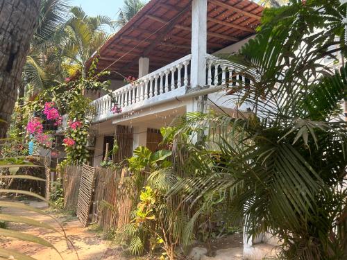 een huis met een veranda met een hek en planten bij Palm Breeze Suites in Palolem