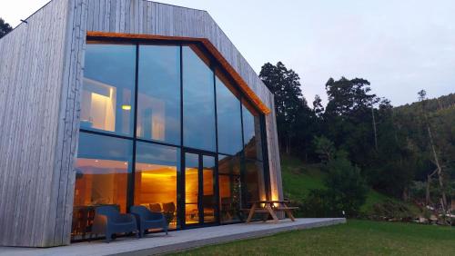 een huis met glazen ramen en een tafel en stoelen bij Sete Cidades Lake Cabin - Casa da Lagoa in Ponta Delgada