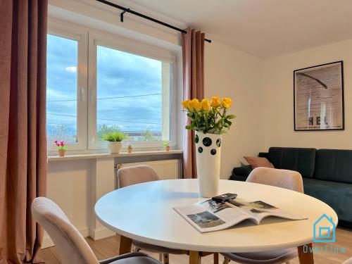 una sala de estar con una mesa y un jarrón con flores amarillas en Hel Apartment, en Borkowo