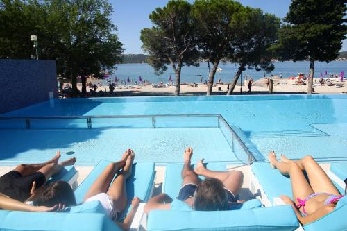 un gruppo di persone che giace in una piscina in una spiaggia di Hotel Adriatic a Biograd na Moru