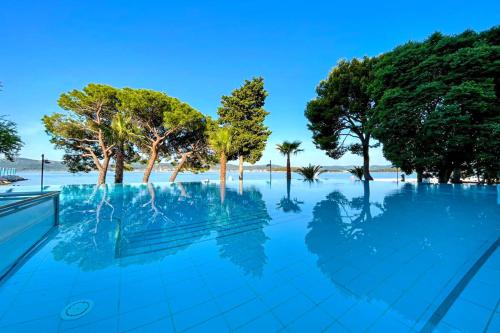 una piscina con alberi e acqua blu di Hotel Adriatic a Biograd na Moru