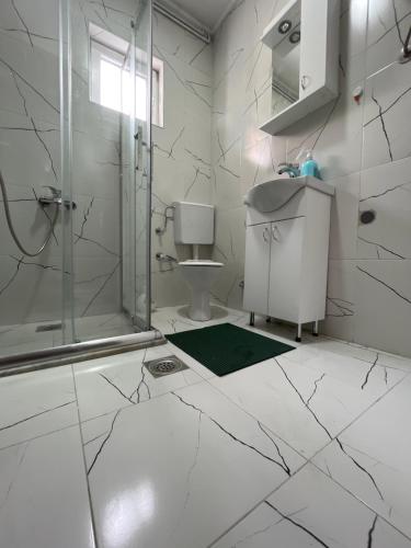 uma casa de banho branca com um chuveiro e um lavatório. em ALOHA apartment em Novi Pazar