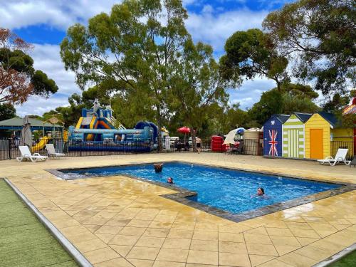 - une piscine sur une aire de jeux avec des gens dans l'eau dans l'établissement BIG4 Port Willunga Tourist Park, à Aldinga