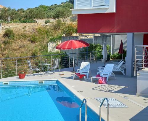 a swimming pool with chairs and a red umbrella at Luxury Apartments Villa Lenka in Podstrana