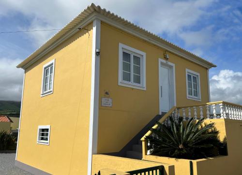 une maison jaune avec une porte blanche dans l'établissement CASA do CAMINHO, à Praia da Vitória