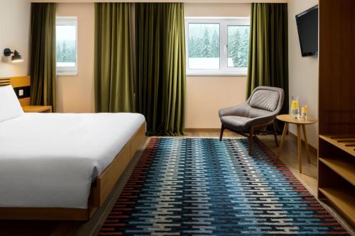 una camera d'albergo con letto e sedia di Ana Hotels Sport Poiana Brasov a Poiana Brasov