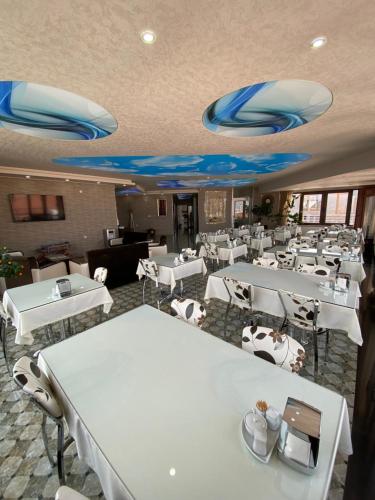 um restaurante com mesas e cadeiras brancas e tecto azul em OTEL KING em Isparta