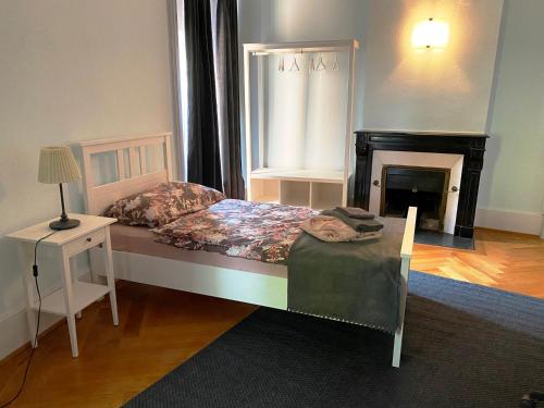 een slaapkamer met een bed, een open haard en een tafel bij Pension Bienvenue (Women only) in Lausanne