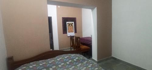 ein kleines Zimmer mit einem Bett und einem Spiegel in der Unterkunft Uthamar Illam in Tiruchchirāppalli