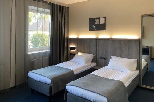 a hotel room with two beds and a window at Brut Wine Hotel in Zarasai