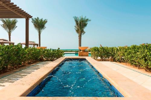 einen Pool in einem Resort mit Palmen in der Unterkunft Ajman Saray, a Luxury Collection Resort, Ajman in Ajman 