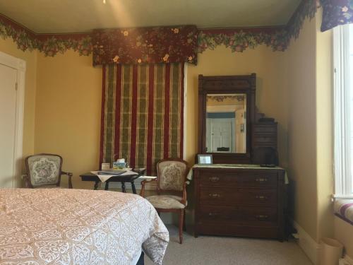 um quarto com uma cama, uma cómoda e um espelho em The Maple Inn em Parrsboro